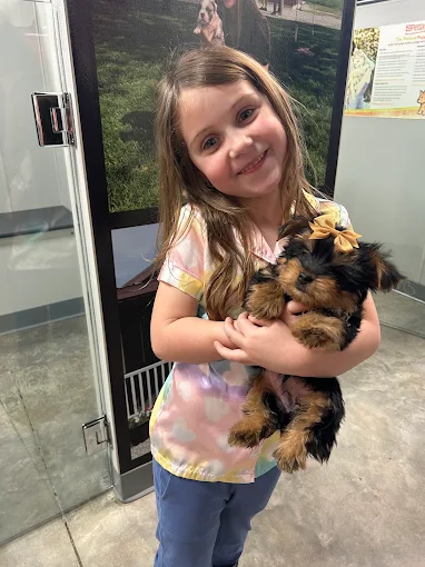 A child holding a puppy at Petland